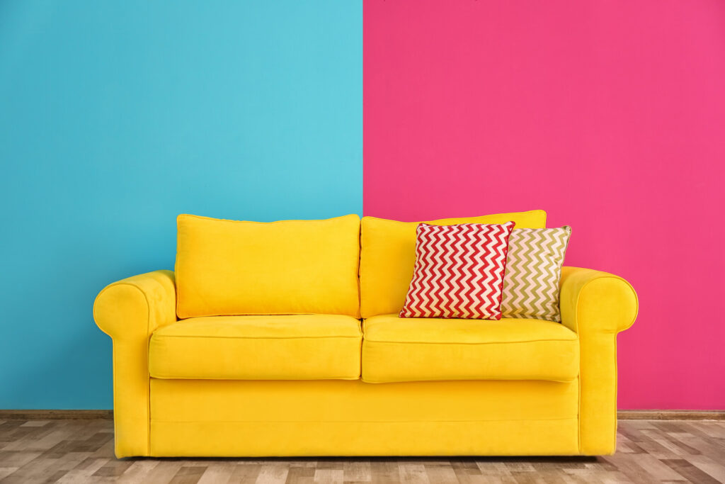 Sofa mit verschiedenen Kissen vor einer zweifarbigen Wand im Zimmer