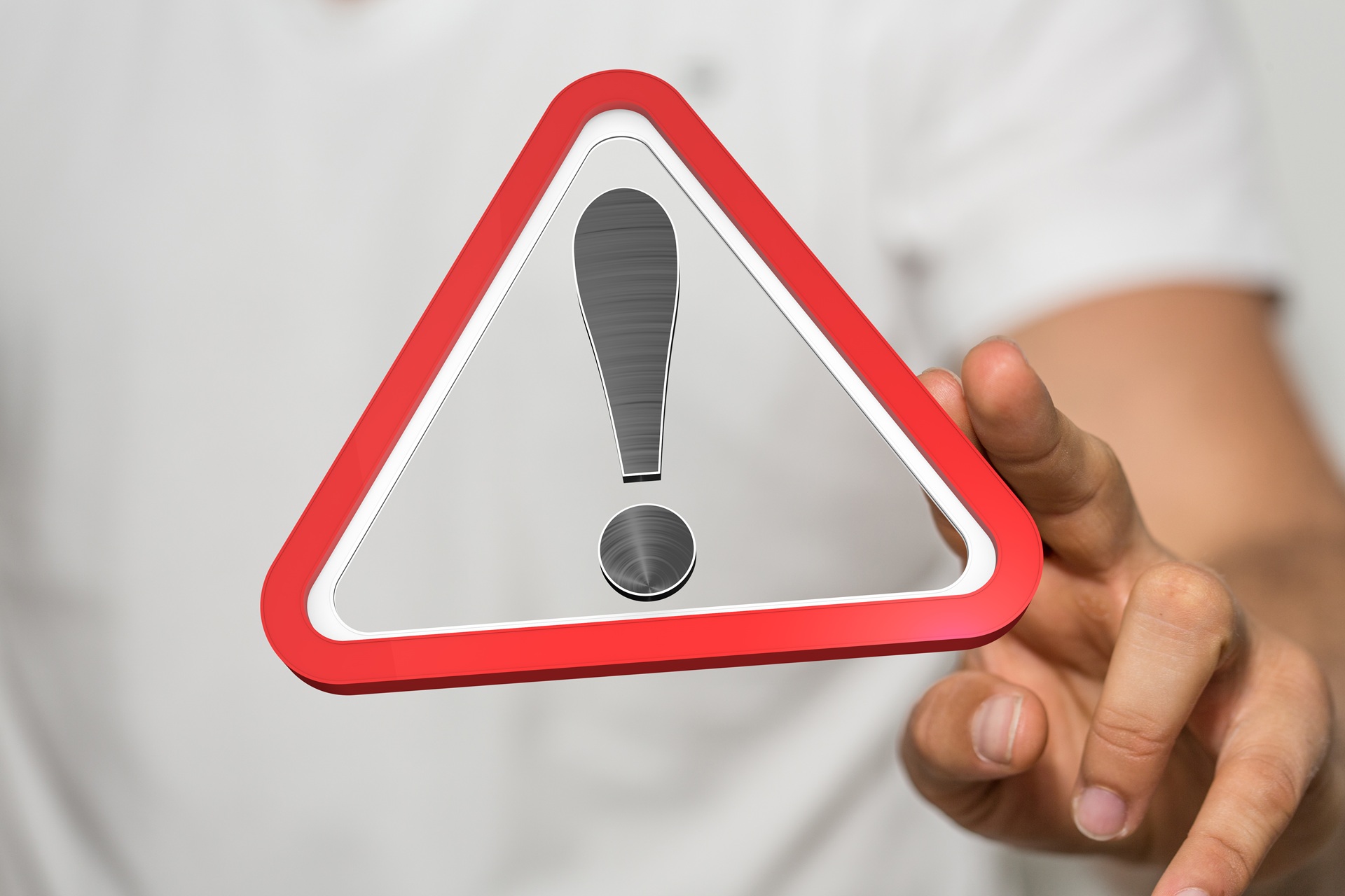 Hand zeigt auf Warnsymbol mit rotem Dreieck und Ausrufezeichen | Dainese